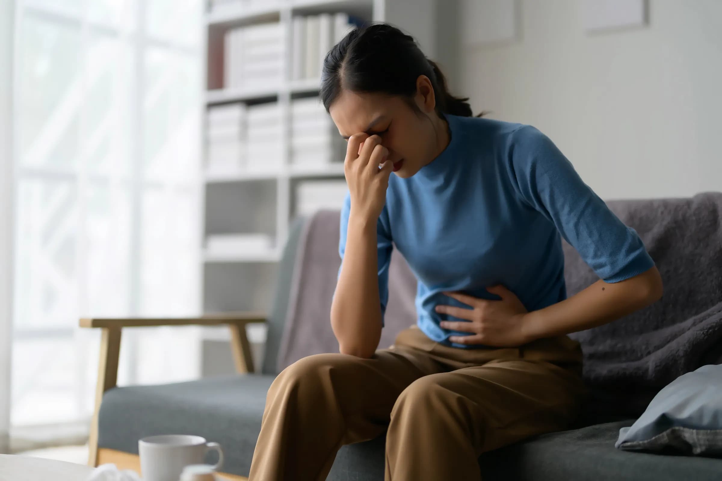 Woman sitting on a sofa holding her abdomen